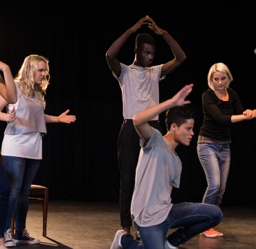 Group of female and male drama students performing