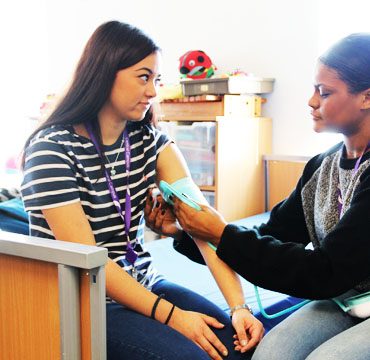 Female Health & Social Care student taking the blood pressure of another female student