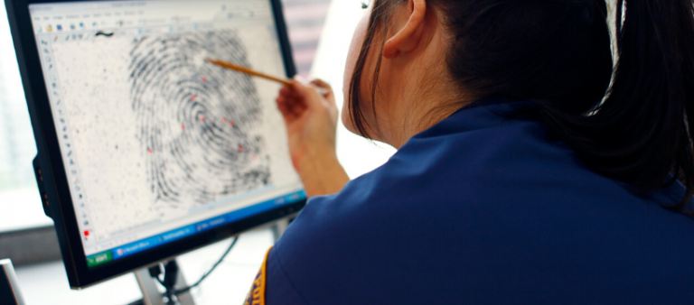 Criminologist analysing fingerprints on a computer