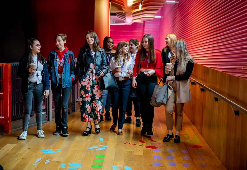 Group of female students talking to each other walking down a corridor at Central Saint Michael's Sixth Form