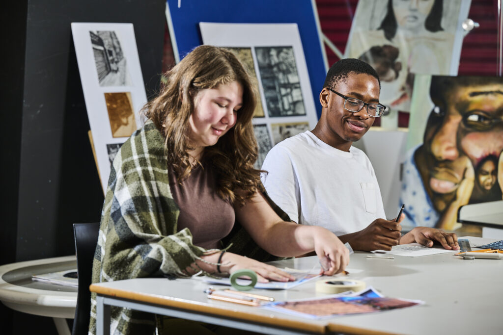 Two students in an art classroom smiling