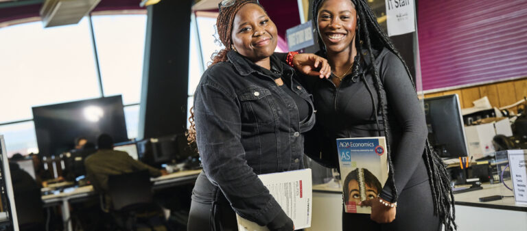 Two female students holding books in the library