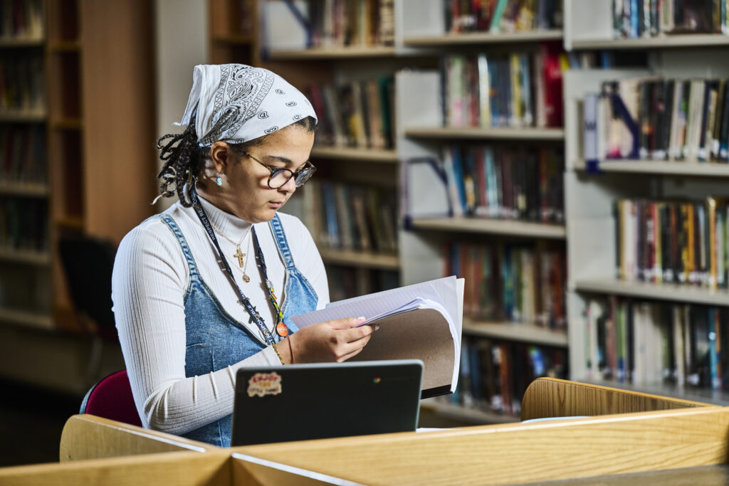 Student flicking through pages with laptop