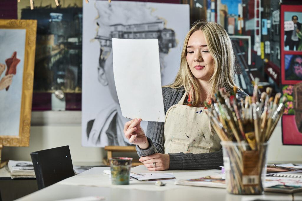 Student in art lesson holding artwork up