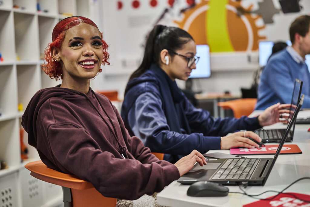 Student on laptop and smiling at the camera