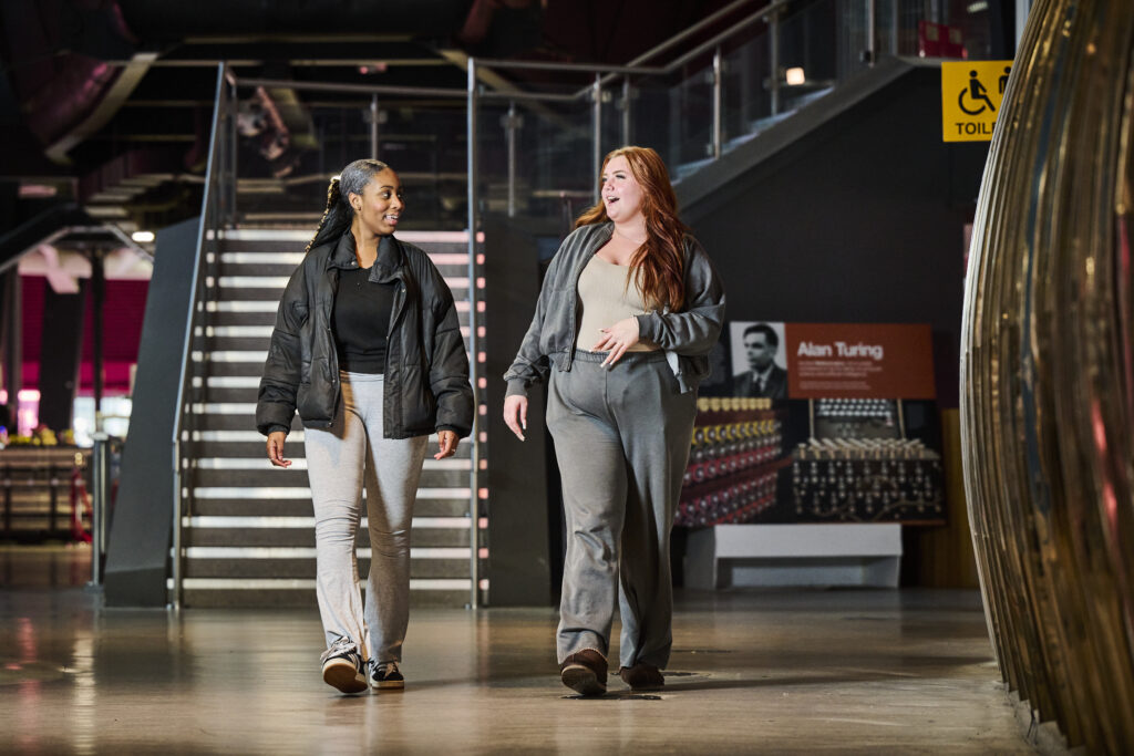 Two students walking on the ground floor smiling