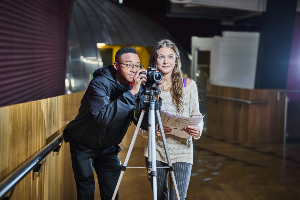 Two students in corridor with camera