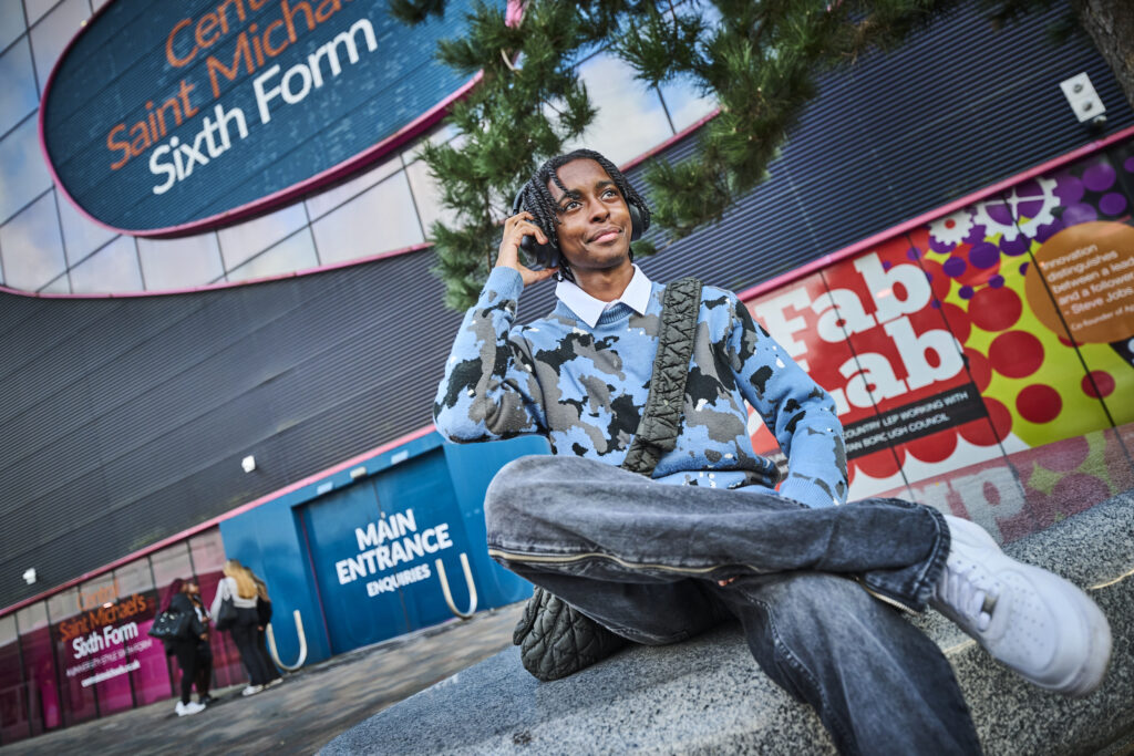 Student outside Central Saint Michaels with headphones on