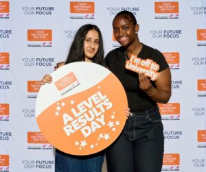 Two students holding orange 'A Level Results Day' sign